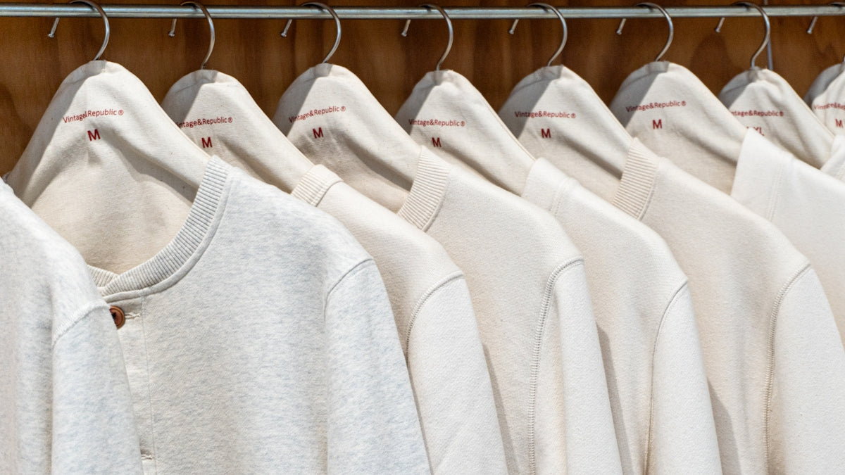 a row of white sweatshirts hanging on a rack